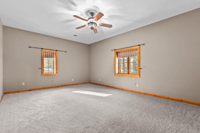 carpeted empty room with baseboards and a ceiling fan