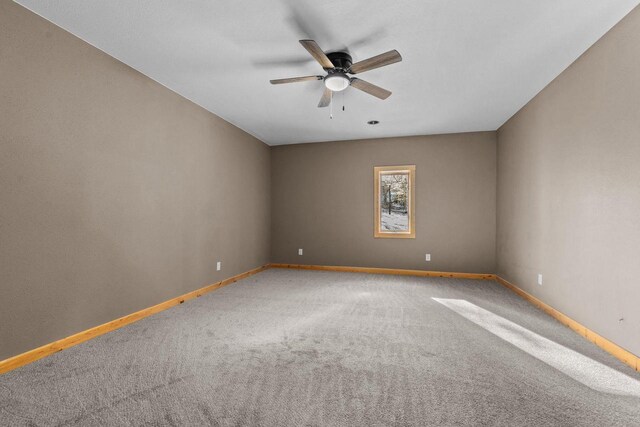 carpeted spare room featuring baseboards and ceiling fan