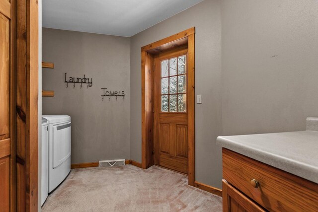 clothes washing area featuring washing machine and dryer, light carpet, laundry area, baseboards, and visible vents