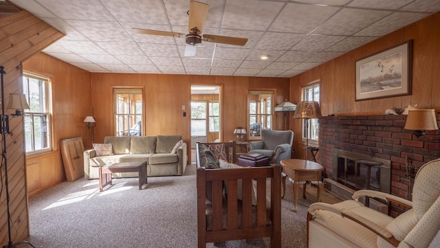 W13573 S Pleasant Rd, Westfield, WI 53964 - carpeted living room featuring a fireplace, a paneled ceiling, wooden walls, and ceiling fan