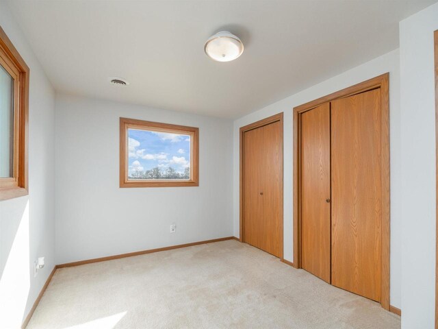 N6741 S Center Rd, Beaver Dam, WI 53916 - unfurnished bedroom with light carpet, baseboards, multiple closets, and visible vents