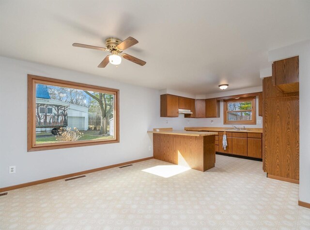 N6741 S Center Rd, Beaver Dam, WI 53916 - kitchen featuring under cabinet range hood, a peninsula, brown cabinetry, and visible vents