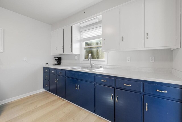 2548 Wallace Lake Rd, West Bend, WI 53090 - kitchen with light countertops, a sink, blue cabinets, light wood-type flooring, and baseboards