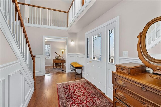 7822 Blue Valley Dr, Eau Claire, WI 54703 - foyer entrance featuring a wainscoted wall, stairs, wood-type flooring, a decorative wall, and a towering ceiling