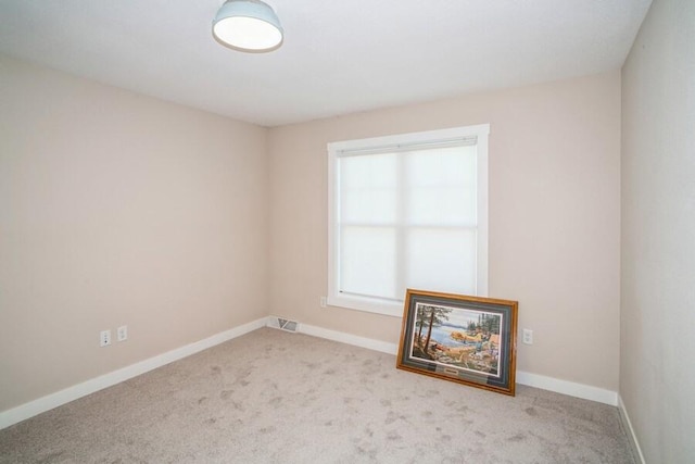 carpeted spare room featuring baseboards and visible vents