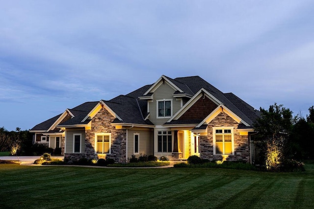craftsman house featuring stone siding and a front yard