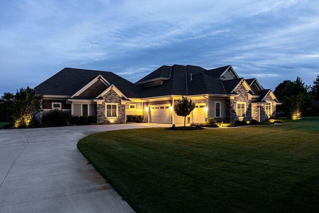 view of front of house featuring stone siding, a garage, concrete driveway, and a front yard