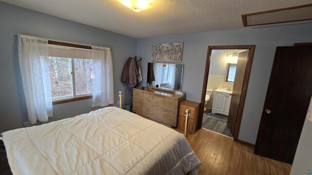 84195 State Highway 13, Bayfield, WI 54814 - bedroom with wood finished floors, a sink, ensuite bath, attic access, and a textured ceiling