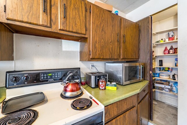 516 Hamilton St, Wausau, WI 54403 - kitchen featuring light countertops, open shelves, white range with electric cooktop, brown cabinetry, and stainless steel microwave
