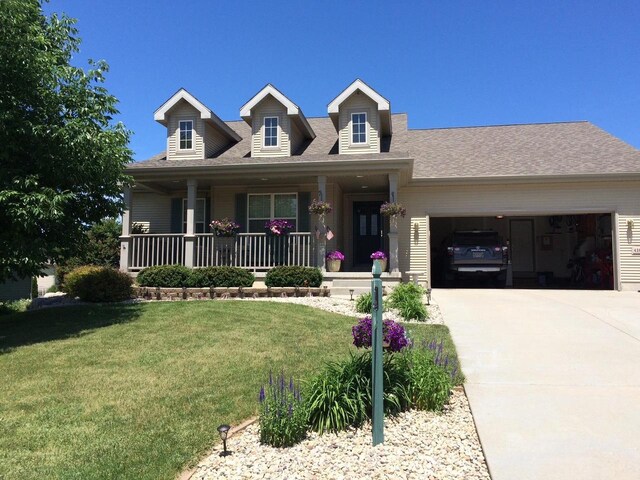 view of front of home featuring a garage, a porch, driveway, and a front lawn