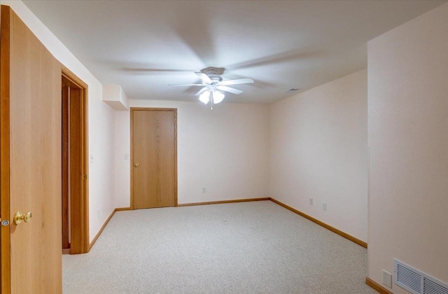carpeted empty room with baseboards, a ceiling fan, and visible vents