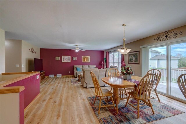 dining area featuring light wood-style floors, a ceiling fan, baseboards, and visible vents