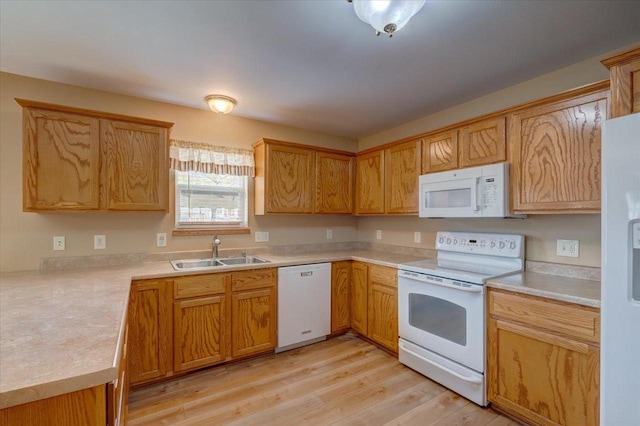 kitchen featuring light wood-type flooring, a sink, white appliances, and light countertops