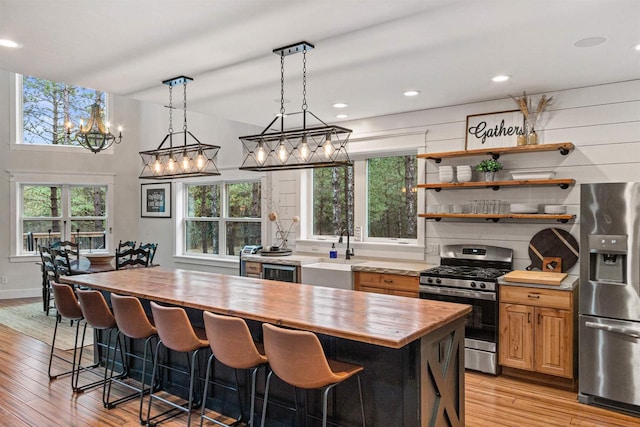 W5430 Southview Dr, Necedah, WI 54646 - kitchen featuring light wood finished floors, stainless steel appliances, a sink, a breakfast bar, and wooden counters