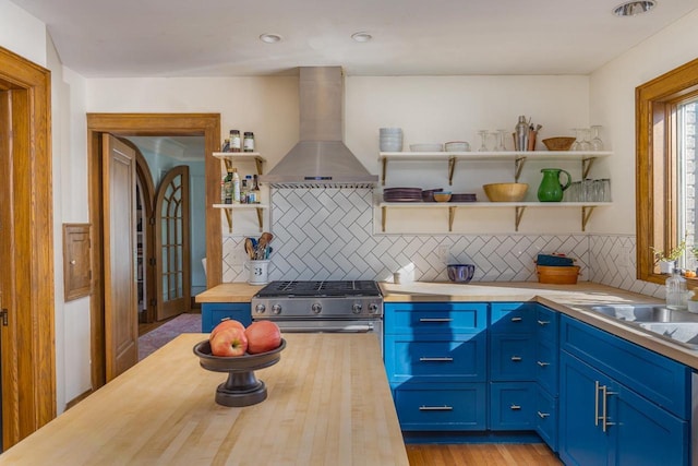 1337 Washington Ave, Oshkosh, WI 54901 - kitchen featuring open shelves, butcher block countertops, blue cabinets, gas stove, and wall chimney exhaust hood