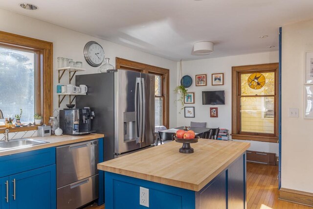 1337 Washington Ave, Oshkosh, WI 54901 - kitchen featuring light wood-style flooring, wooden counters, appliances with stainless steel finishes, a sink, and blue cabinets