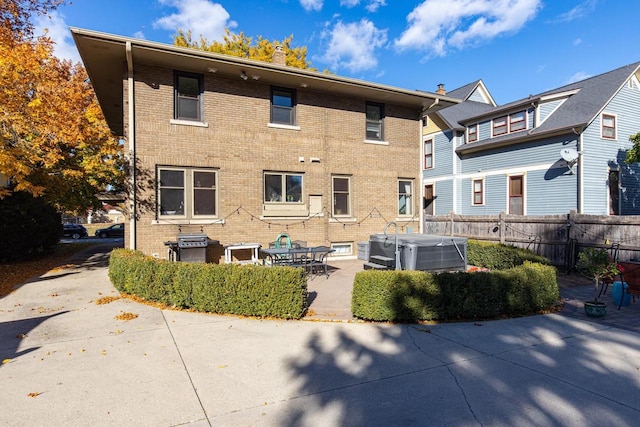 1337 Washington Ave, Oshkosh, WI 54901 - rear view of property with cooling unit, fence, a hot tub, a patio, and brick siding