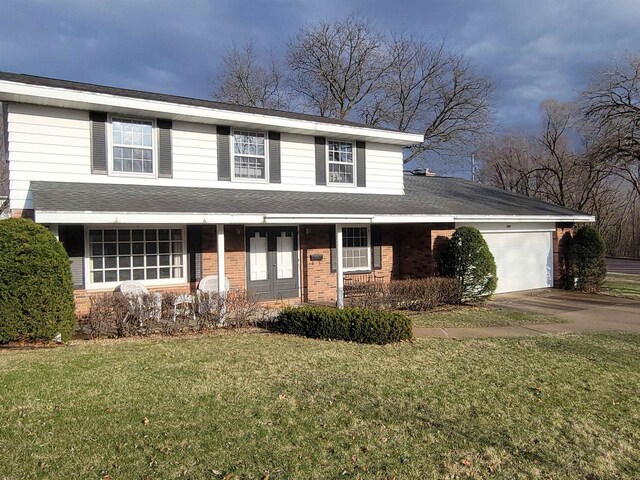 302 Riverview Ct, Portage, WI 53901 - traditional-style home featuring a front lawn, driveway, a garage, and brick siding
