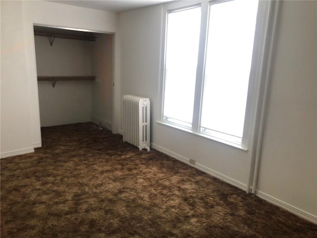 609 S Dewey St, Eau Claire, WI 54701 - unfurnished bedroom featuring baseboards, dark carpet, a closet, and radiator heating unit