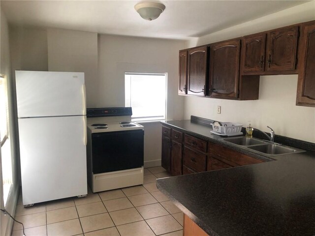 609 S Dewey St, Eau Claire, WI 54701 - kitchen with dark countertops, a sink, range with electric stovetop, light tile patterned floors, and freestanding refrigerator