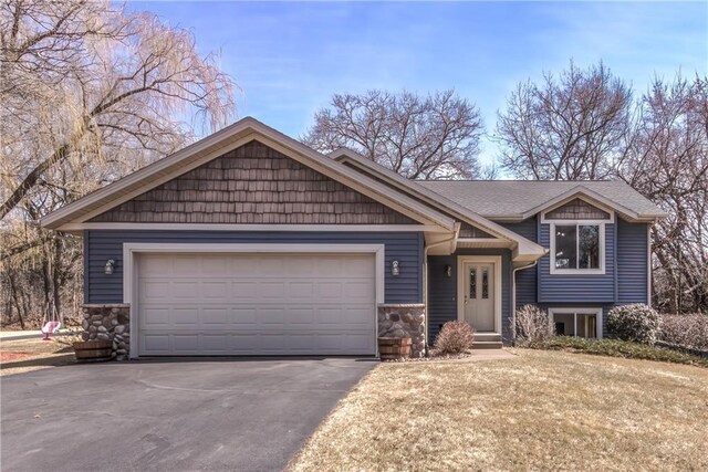 view of front of house featuring an attached garage, stone siding, and aphalt driveway