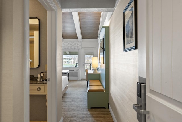 hall featuring baseboards, beamed ceiling, and carpet floors