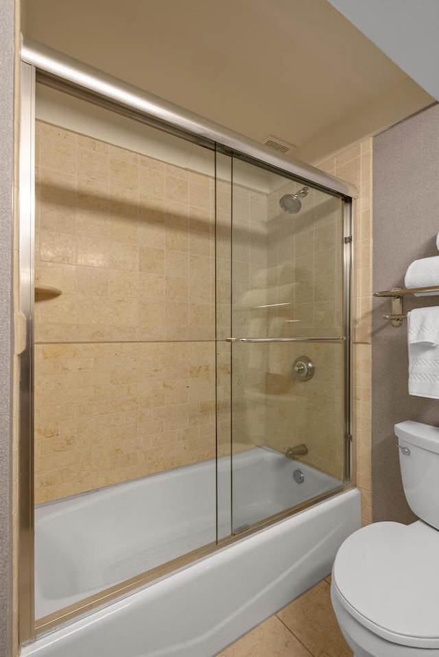 full bathroom with tile patterned floors, toilet, and shower / bath combination with glass door