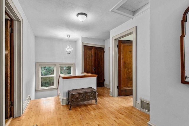 2346 Hickory Ln, Oshkosh, WI 54901 - hallway with an upstairs landing, wood-type flooring, ornamental molding, visible vents, and a notable chandelier