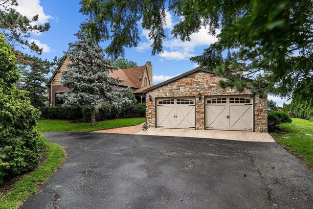 2346 Hickory Ln, Oshkosh, WI 54901 - view of front of home with stone siding, a chimney, an outbuilding, a front lawn, and a garage