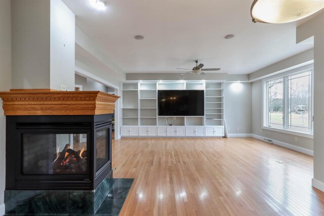 1579 Foxfire Ct, Waupaca, WI 54981 - living area with baseboards, a ceiling fan, a multi sided fireplace, and light wood finished floors