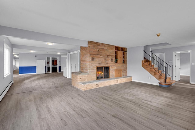 unfurnished living room with baseboards, a fireplace, wood finished floors, and stairway