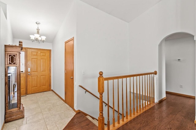 entryway featuring arched walkways, vaulted ceiling, baseboards, and an inviting chandelier