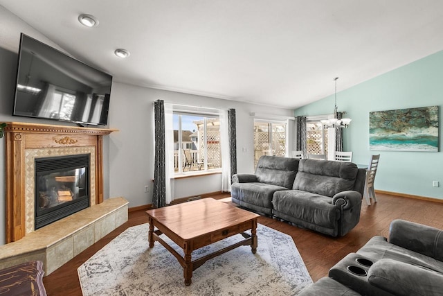 living area featuring baseboards, a notable chandelier, wood finished floors, a premium fireplace, and lofted ceiling