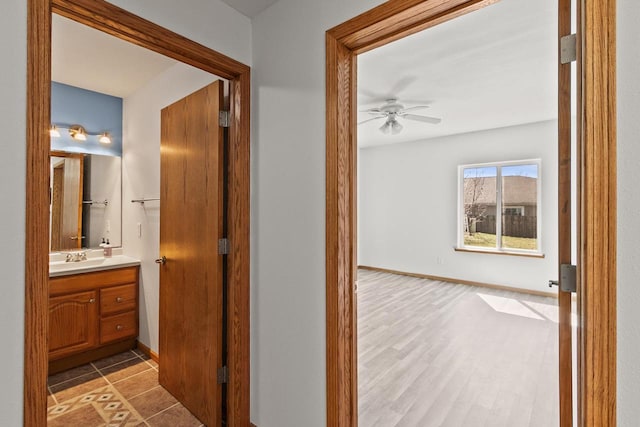 corridor with wood finished floors, a sink, and baseboards