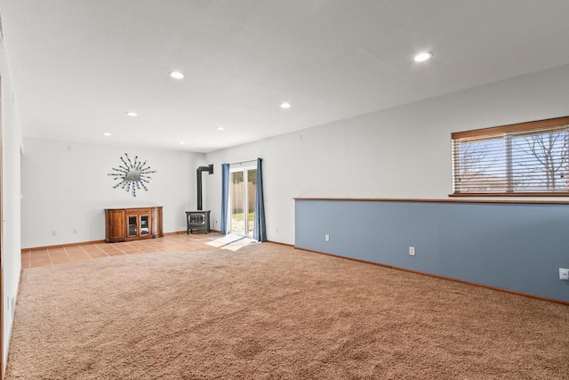 unfurnished living room featuring a wood stove, baseboards, carpet, and recessed lighting