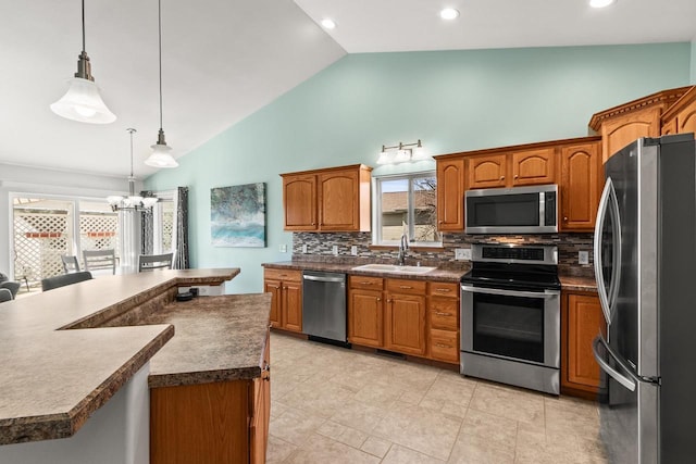 kitchen with brown cabinets, appliances with stainless steel finishes, a sink, and dark countertops