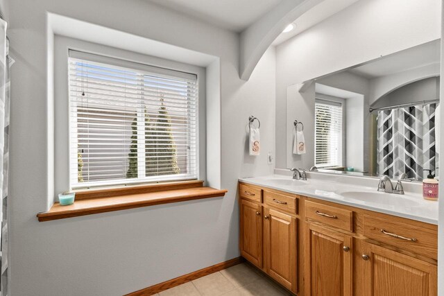 bathroom with tile patterned flooring, double vanity, baseboards, and a sink