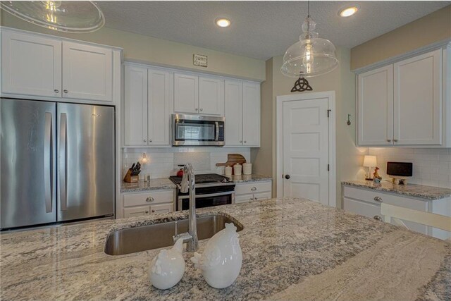 102 Linden Ave, Hudson, WI 54016 - kitchen with white cabinetry, decorative light fixtures, backsplash, and stainless steel appliances