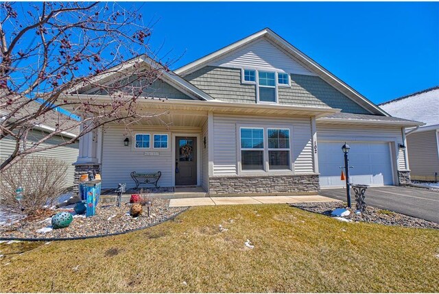 102 Linden Ave, Hudson, WI 54016 - view of front of house featuring stone siding, a garage, a front yard, and aphalt driveway