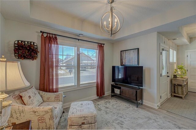 102 Linden Ave, Hudson, WI 54016 - living area with a tray ceiling, baseboards, light wood-type flooring, and an inviting chandelier