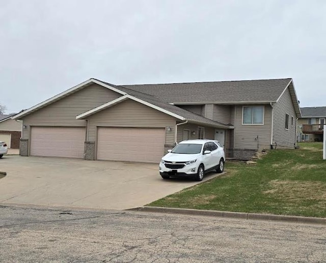 split level home with an attached garage, a front lawn, and concrete driveway