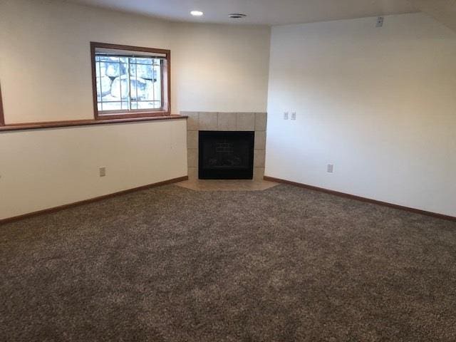 unfurnished living room with baseboards, a tiled fireplace, carpet flooring, and recessed lighting