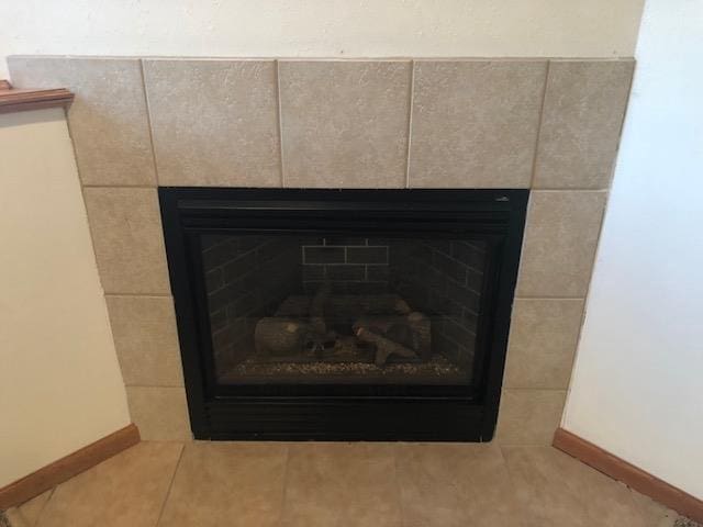 interior details featuring a tile fireplace and baseboards