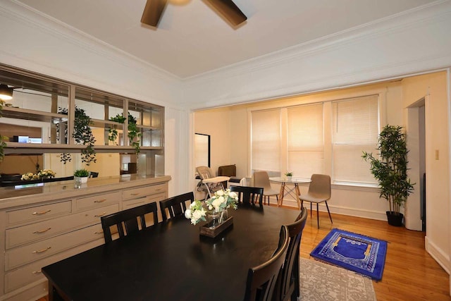 dining space featuring baseboards, crown molding, light wood-style floors, and a ceiling fan