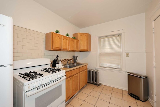 kitchen with tasteful backsplash, white appliances, a sink, light tile patterned flooring, and radiator heating unit