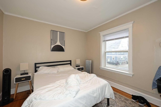 bedroom with wood finished floors, radiator heating unit, and ornamental molding