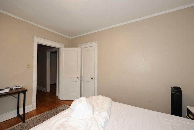 bedroom featuring ornamental molding, baseboards, and wood finished floors