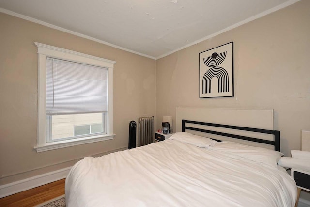 bedroom with radiator, wood finished floors, and ornamental molding