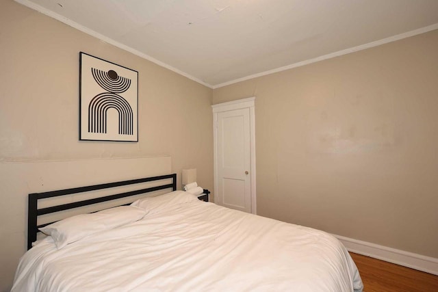 bedroom with baseboards, wood finished floors, and ornamental molding