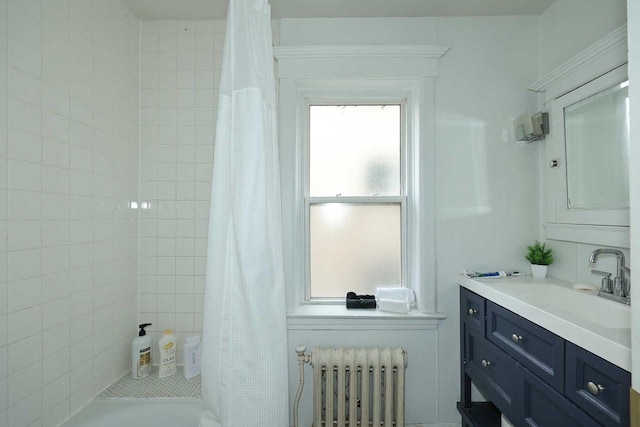 bathroom with radiator, tiled shower, and vanity